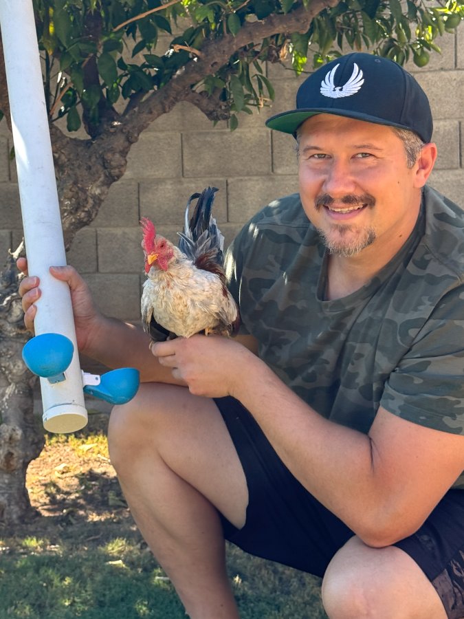 Customer photo: a keeper holding a PVC watering line fitted with blue Lil'Clucker cups